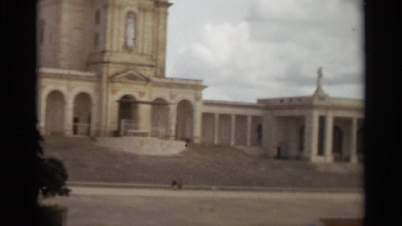 1965 Nazare, Portugal frame with a tower edge, arched entrance, colonnade, steps, and tiny distant people.