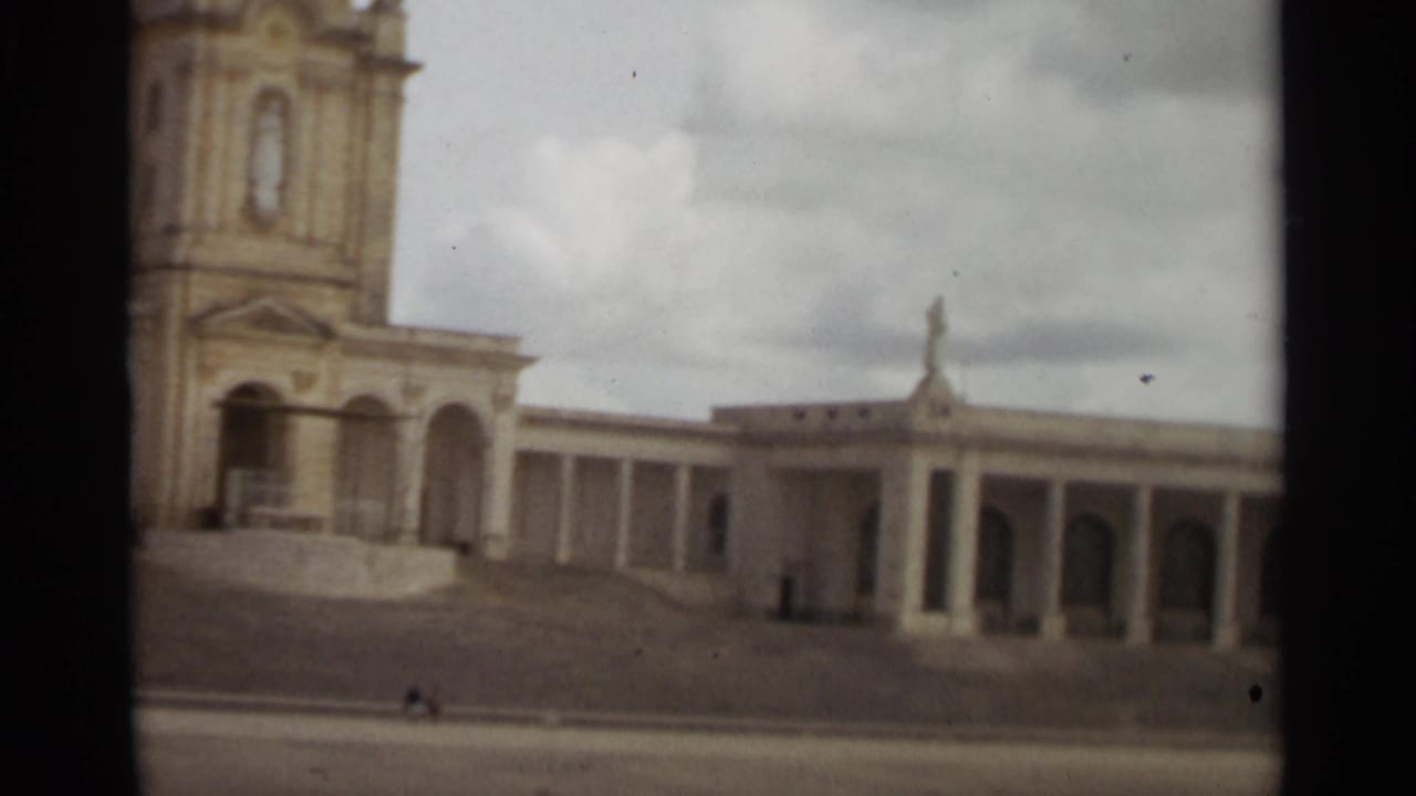 1965 Nazare, Portugal 8mm frame showing the colonnaded side wing, arched bays, and distant visitors.
