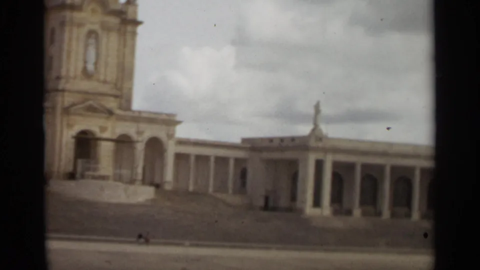 1965 Nazare, Portugal 8mm frame showing the colonnaded side wing, arched bays, and distant visitors.