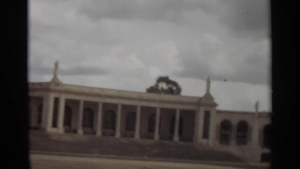 1965 Nazare frame centered on a long colonnade with arched bays, broad steps, and cloudy sky.