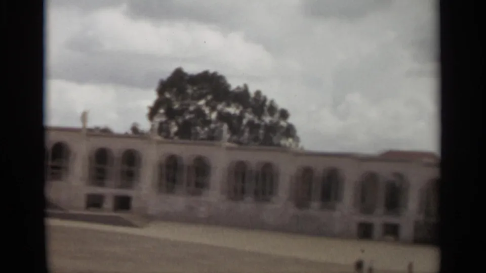 1965 Nazare frame showing the end of the arched facade, trees behind the building, and open paved ground.