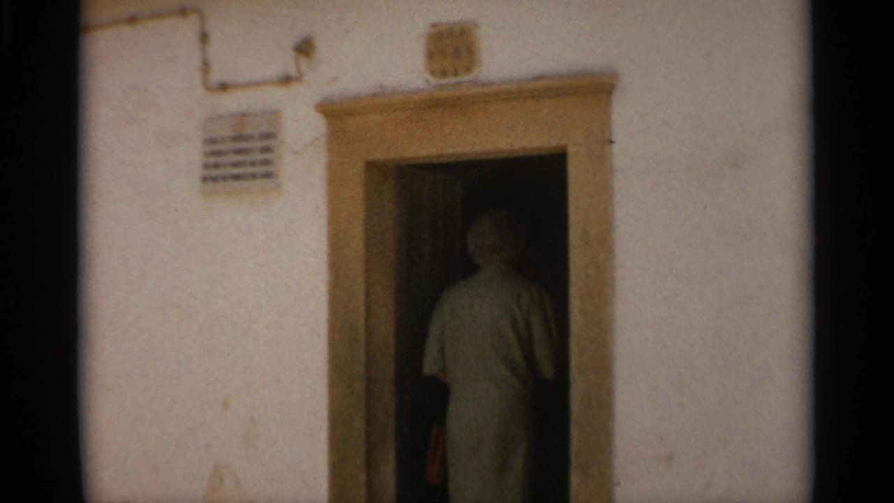 Person in light clothing entering a dark doorway in a white wall.