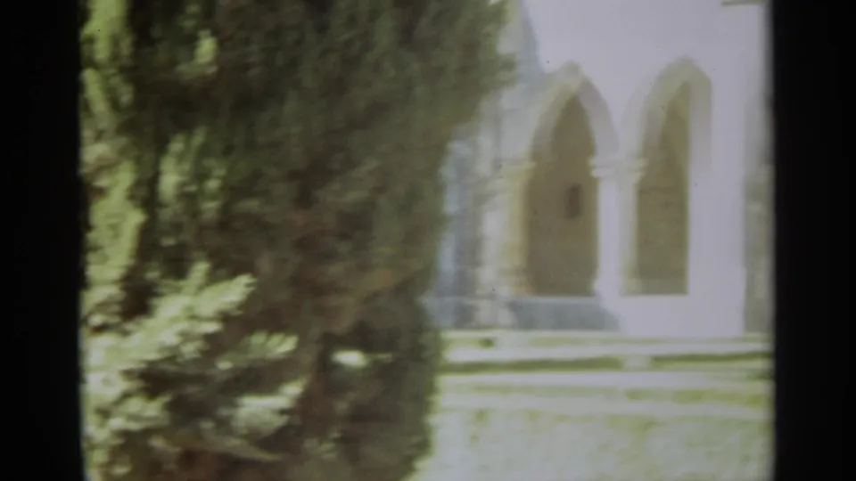 1965 Nazaré, Portugal frame of a historic religious courtyard with cypress trees before arched stone openings.