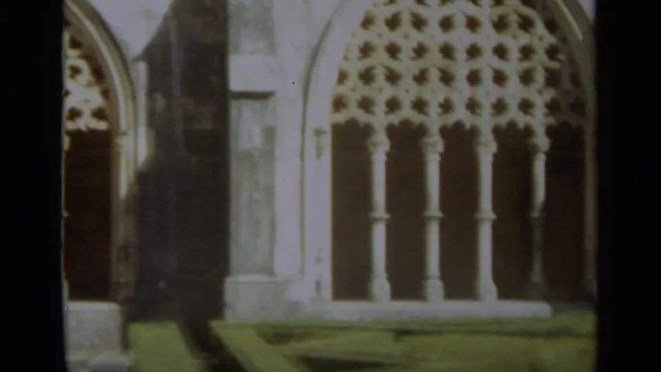 1965 Nazaré, Portugal 8mm still showing decorative stone tracery and columns in a religious courtyard arcade.