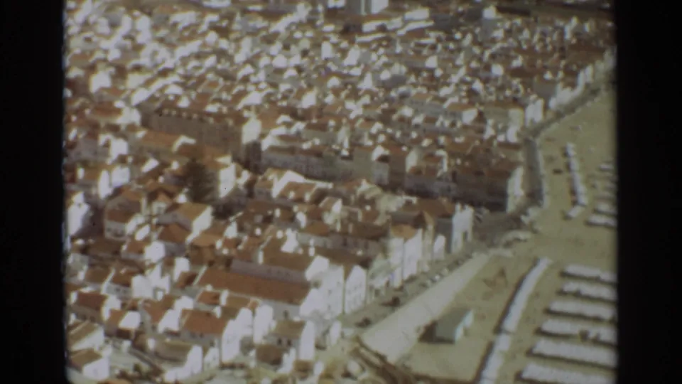 1965 8mm aerial view over Nazare, Portugal, showing white buildings with terracotta roofs near the beach.
