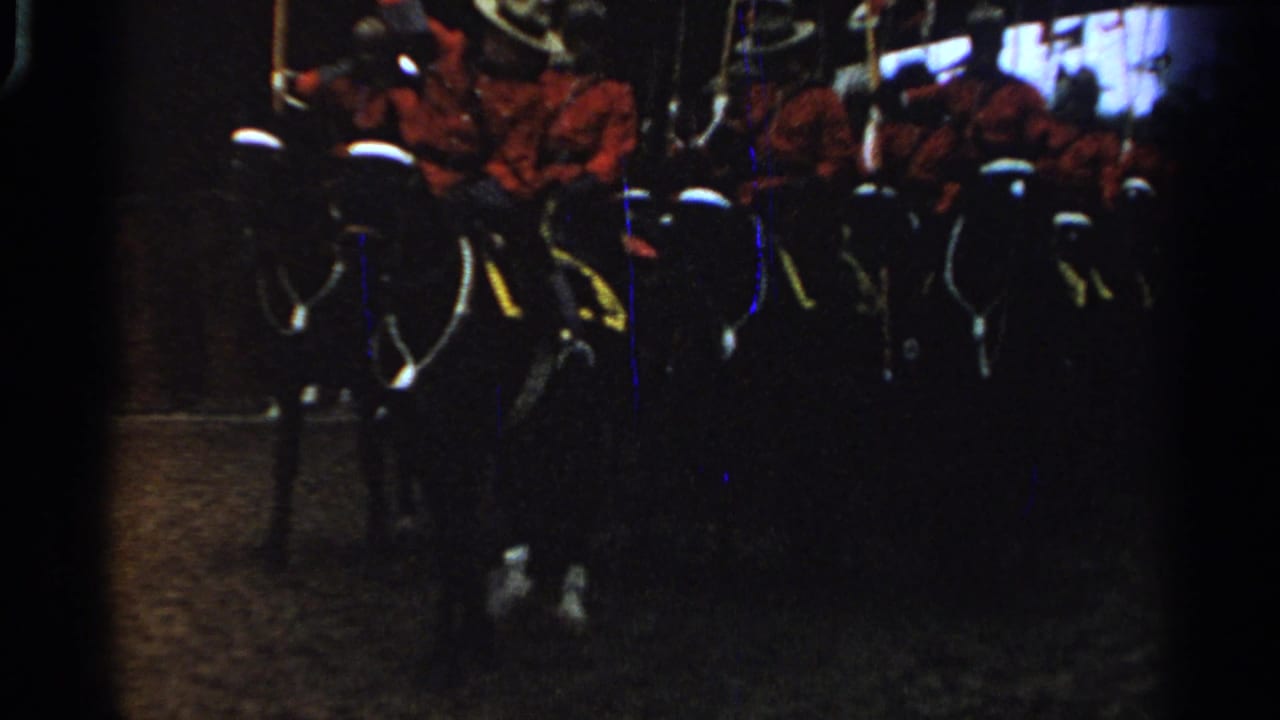 Mounted men in red uniforms and white helmets pass through a dim 1965 Saint Louis procession frame.