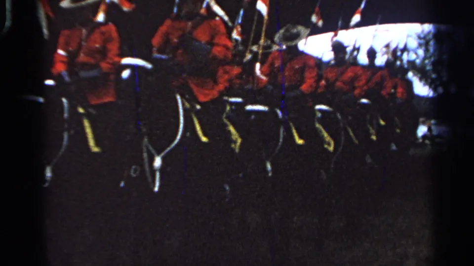 A formation of mounted men in red uniforms and white helmets continues past the home-movie camera in Saint Louis.