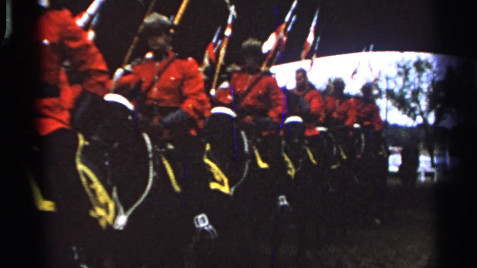 A close spectator view shows red-uniformed mounted riders and dark horses moving through a ceremonial formation in Saint Louis metadata context.