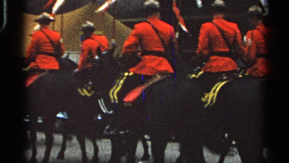 The home-movie view shifts behind the mounted group as red-jacketed riders continue away along the parade route.
