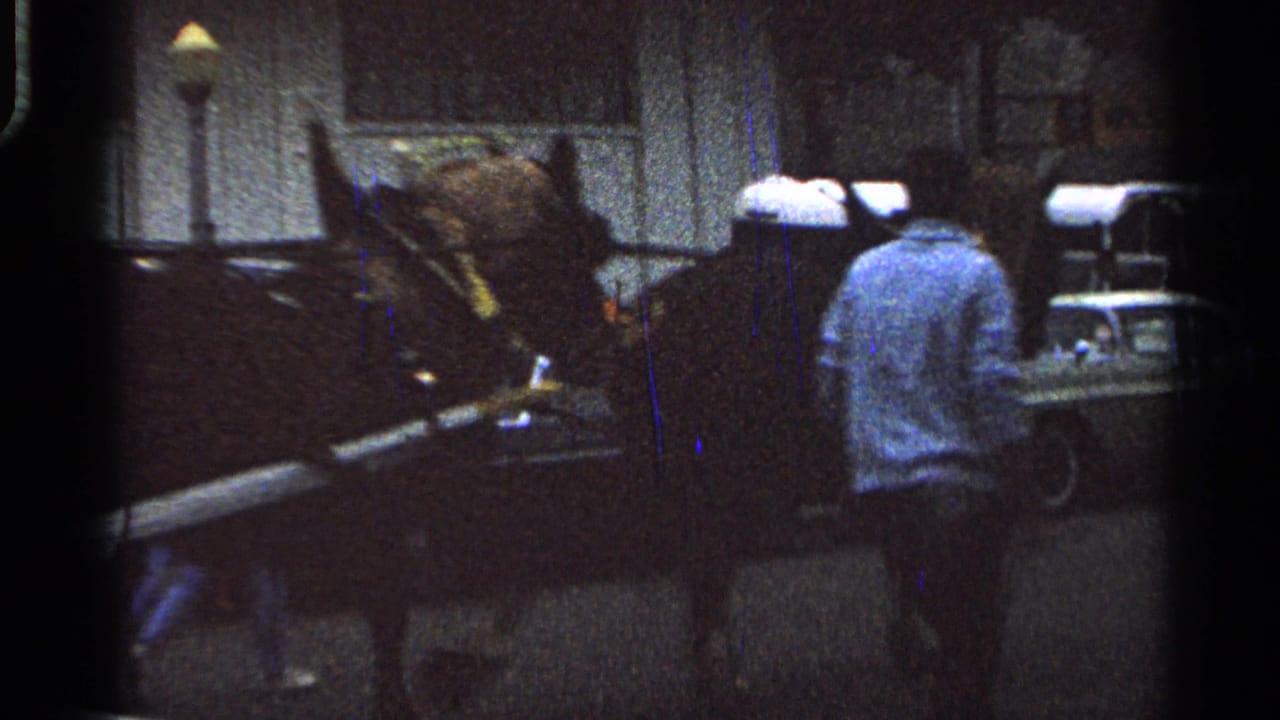 Horse-drawn buggy beside cars at a dim fairground with a man standing near the horse.