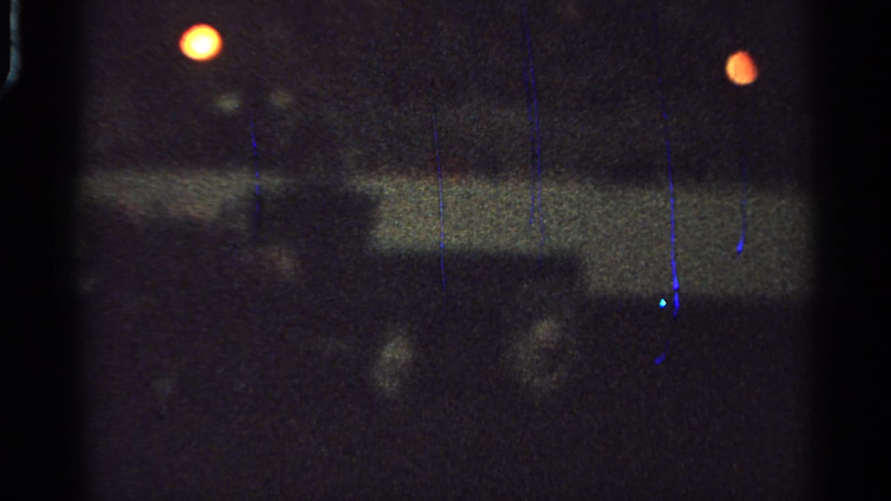 1965 Saint Louis 8mm frame with two orange lights above a dim horizontal rail or barrier and indistinct movement below.