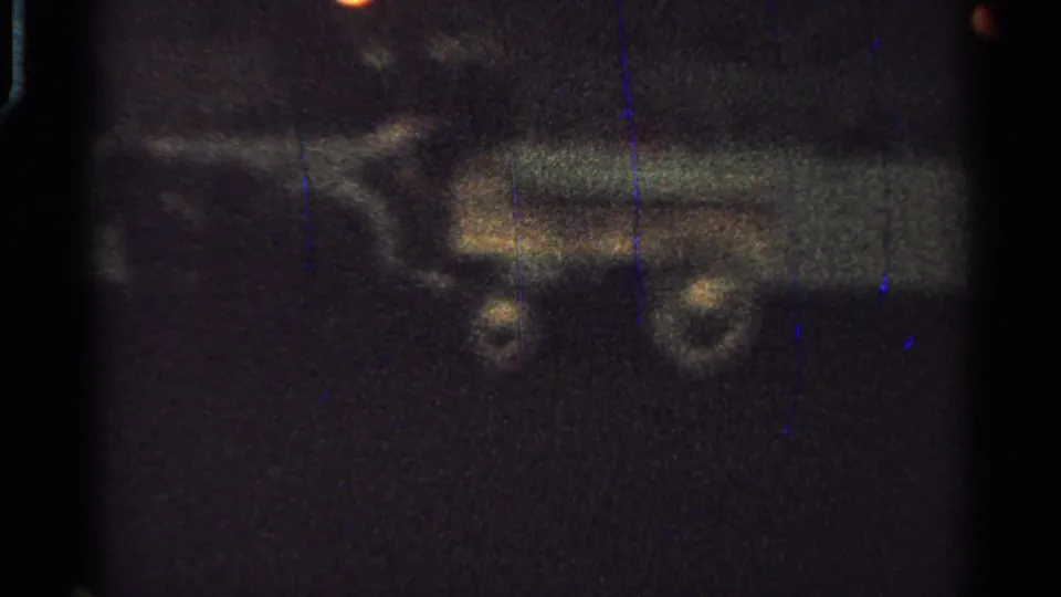 1965 Saint Louis 8mm frame with a pale rail-like band and indistinct paired dark shapes that may be horses or carts in shadow.