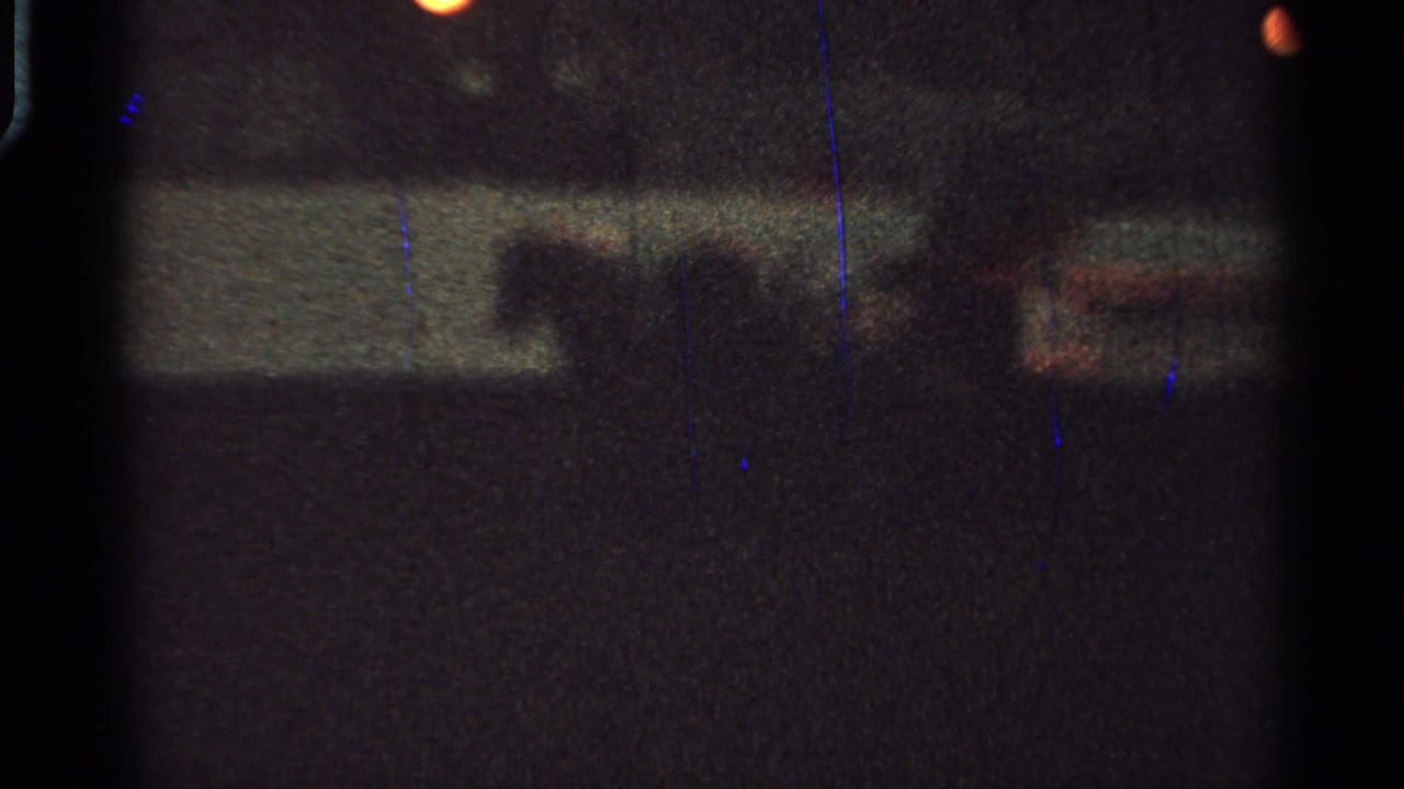 Dark, blurry nighttime street view with faint lights and indistinct carriage shapes.