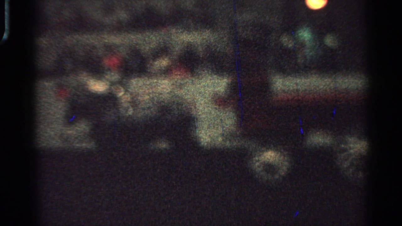 A low-light 8mm frame shows the carriage near dim lights and indistinct people on a Saint Louis street in 1965.