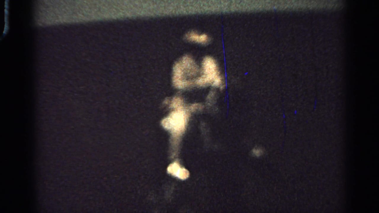 A distant rider in light-toned clothing appears above a dark nighttime parade scene.