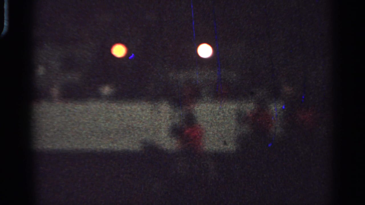 1965 Saint Louis night parade view with red-coated mounted riders behind a low barrier under artificial lights.
