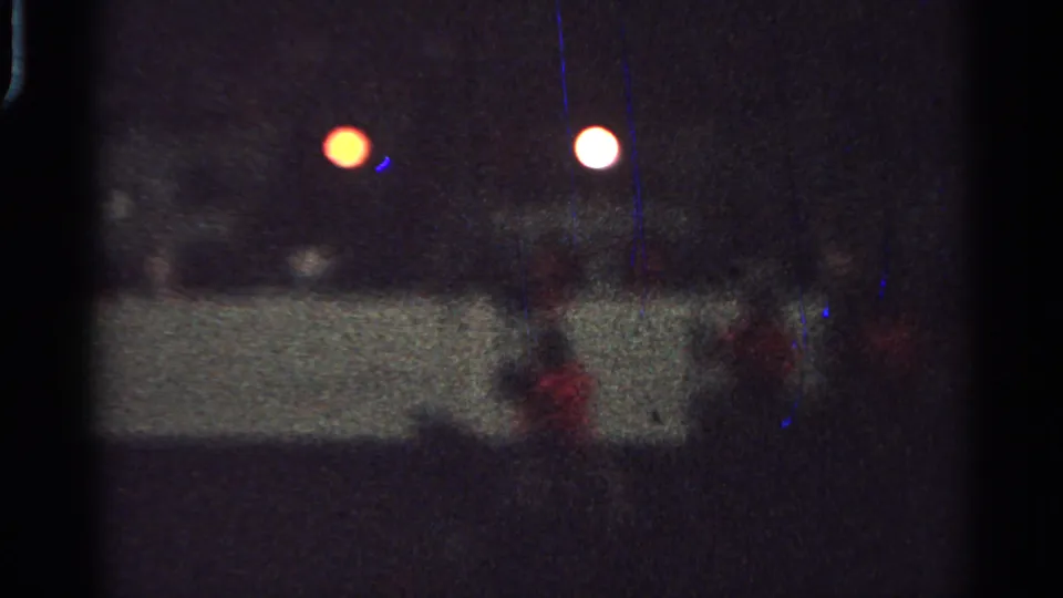 1965 Saint Louis night parade view with red-coated mounted riders behind a low barrier under artificial lights.