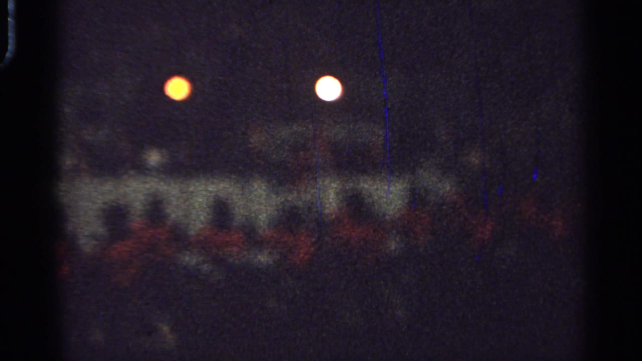 Soft low-light view of a group passing beneath orange and white lights.