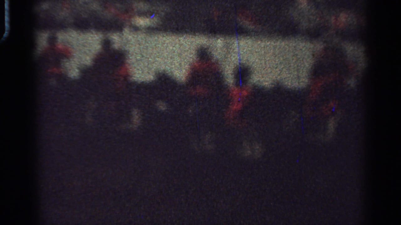 Low-light 8mm view of red-coated mounted riders crossing the frame in Saint Louis, Missouri, in 1965.