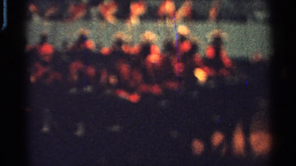 Blurred 1965 Saint Louis parade frame with red-jacketed horseback riders and spectators visible behind the arena barrier.