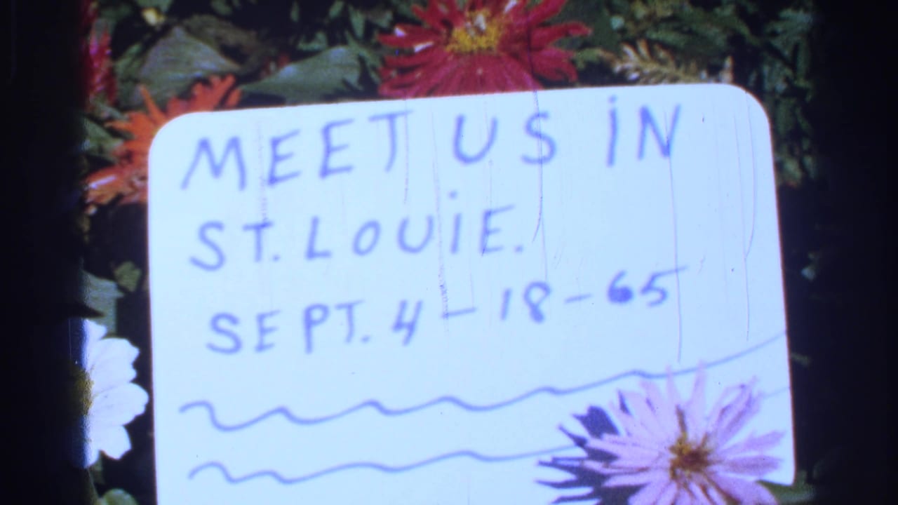 Handwritten Saint Louis gathering card dated Sept. 4-18-65, framed by red, pink, and white flowers on 8mm film.