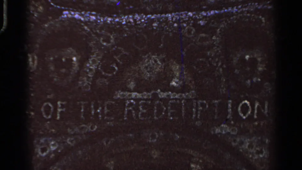 Dark, grainy 8mm frame showing the Grotto of the Redemption inscription on a weathered stone surface.