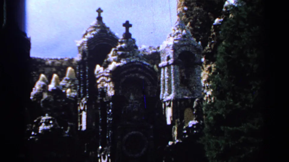 1965 Saint Louis home-movie view of cross-topped stone structures, arched forms, foliage, and strong shadow.