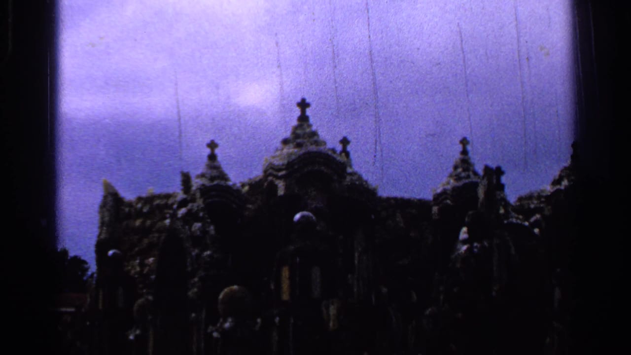 Shadowed religious monument details with crosses and spires under a tinted sky.