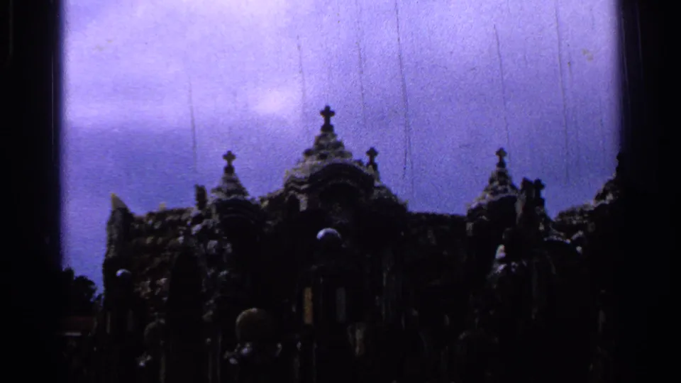 1965 Saint Louis home-movie frame of a dark ornate religious monument with crosses, spires, and visible film scratches.