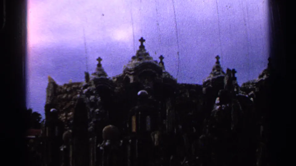 1965 Saint Louis 8mm frame showing a Gothic-style religious monument in heavy shadow with crosses and purple color shift.