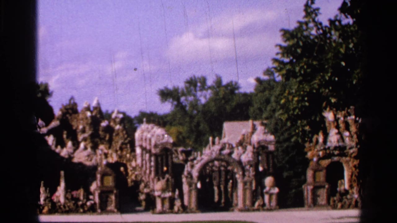 1965 Saint Louis 8mm frame with decorative stone archways, carved-looking garden forms, trees, lawn, and visible dark film borders.