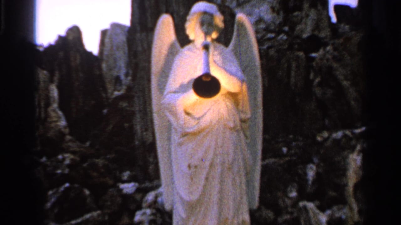 The winged angel statue is framed closer in the 1965 Saint Louis home-movie footage, with its horn and robe visible in low light.