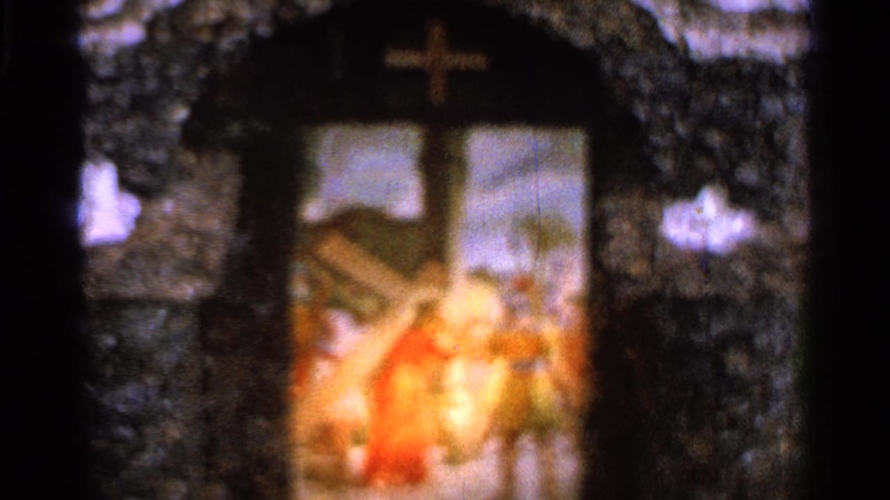 The camera holds on the shrine arch and painted Passion scene, with soft focus, saturated color, and visible 8mm frame edges.