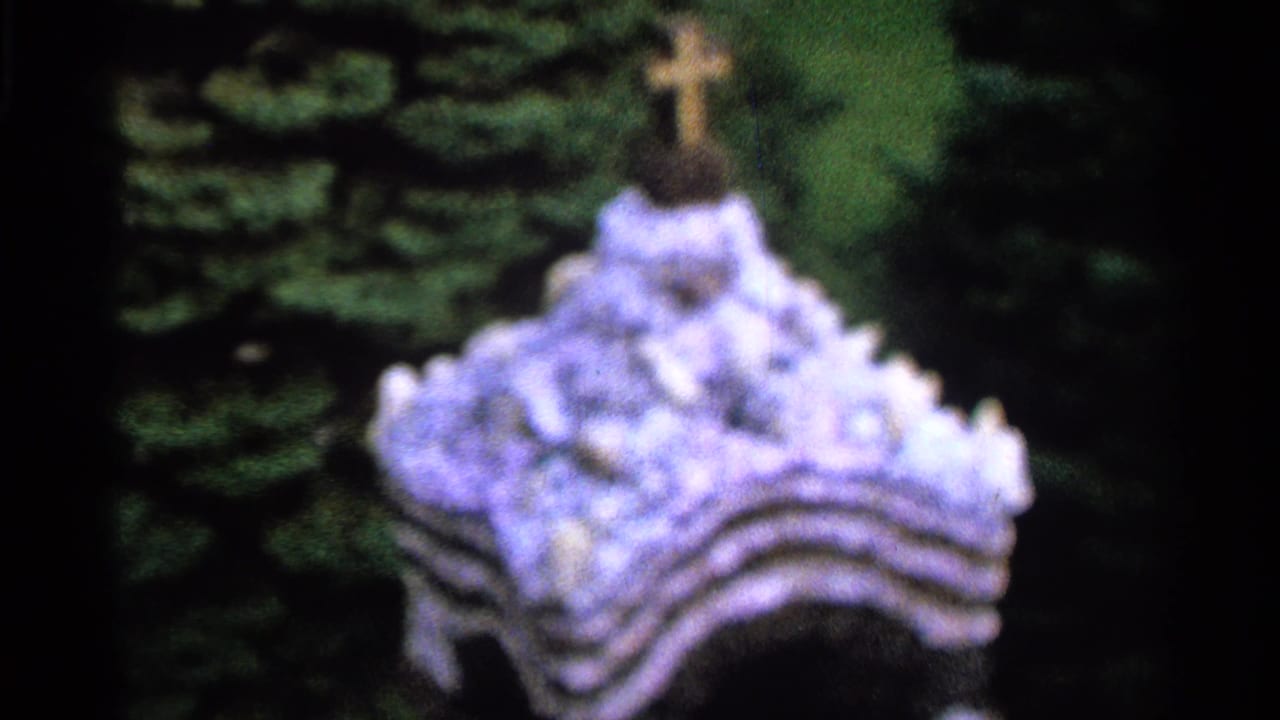 A lower view shows a pale tiered shrine or decorative base with a cross rising above it, set against dark green foliage.