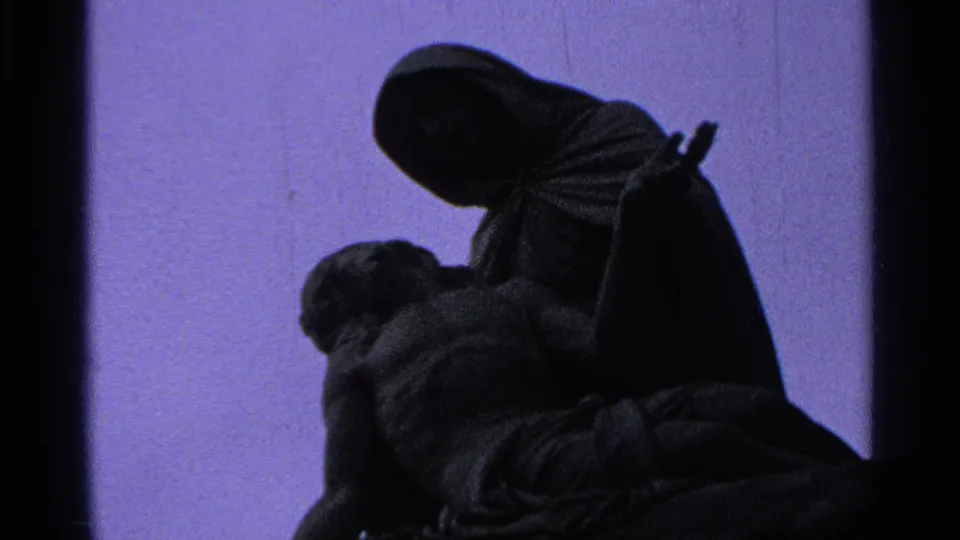 Close 1965 8mm view of the Madonna and Christ statue, with the figures mostly in shadow and purple color shift.