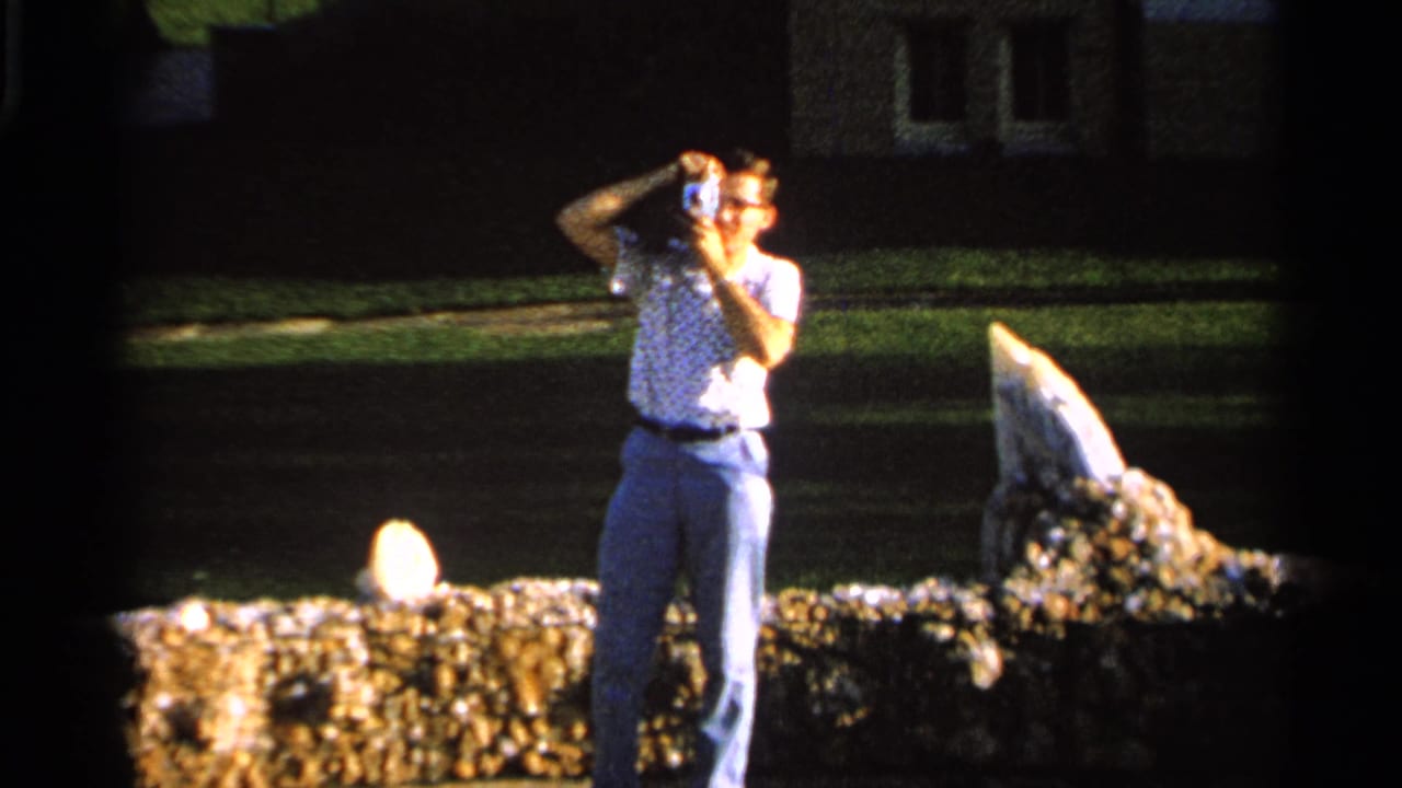 A man in glasses and a patterned shirt photographs the scene with a handheld camera in Saint Louis, Missouri, 1965.