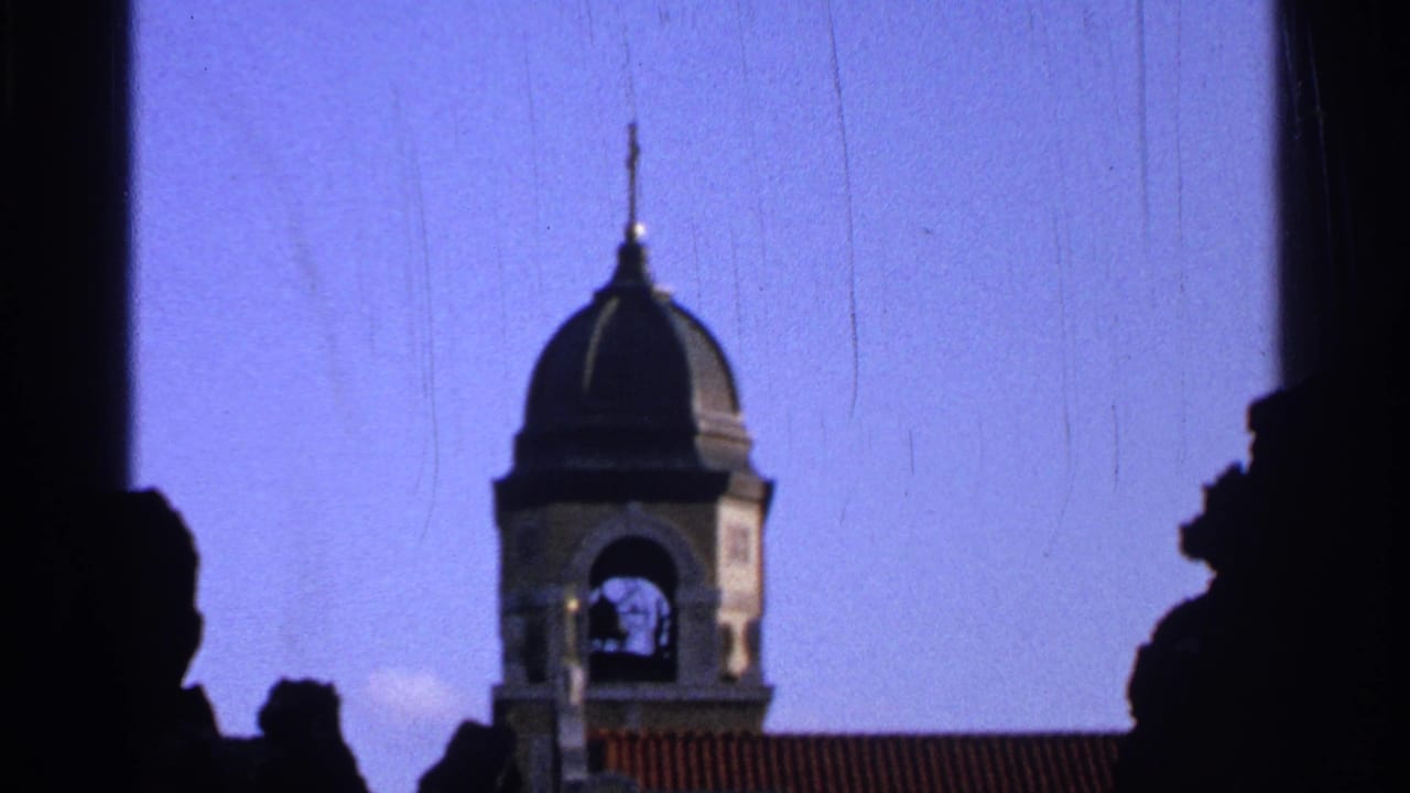 Black domed bell tower seen against a blue sky with dark silhouettes in the foreground.