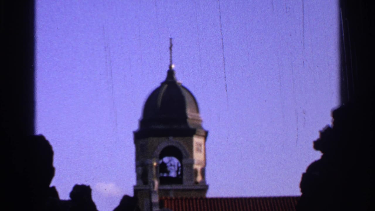 1965 Saint Louis home-movie frame of a black domed bell tower and roofline, bordered by silhouetted foreground forms.