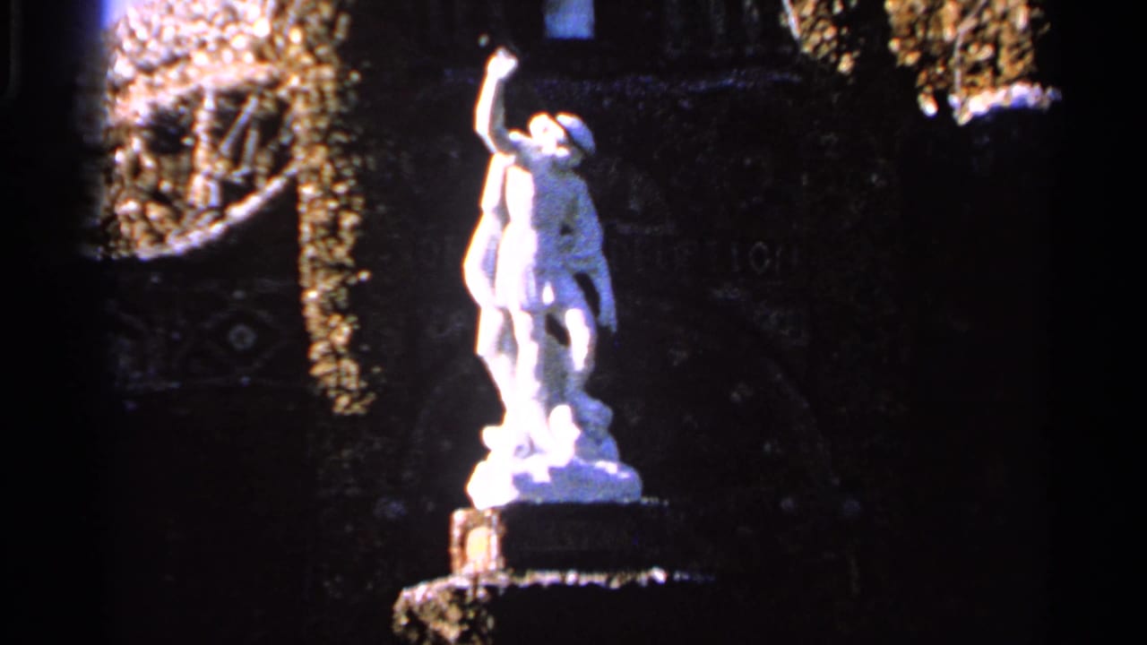 White statue on a pedestal, filmed in Saint Louis in 1965, with dark masonry and trailing greenery around it.
