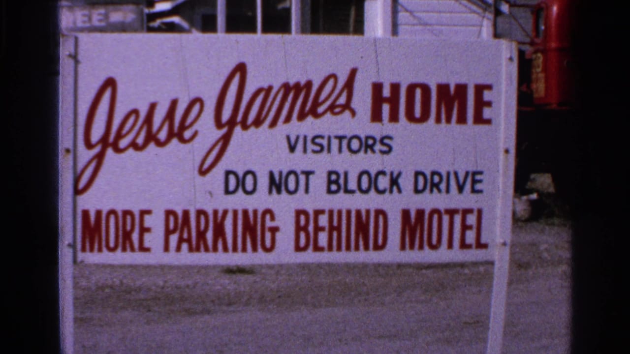 White Jesse James Home visitor sign with parking instructions beside a building.