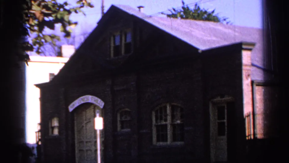 1965 Saint Louis frame holding on the Pony Express Stables facade, with the arched doors and street sign prominent in the foreground.