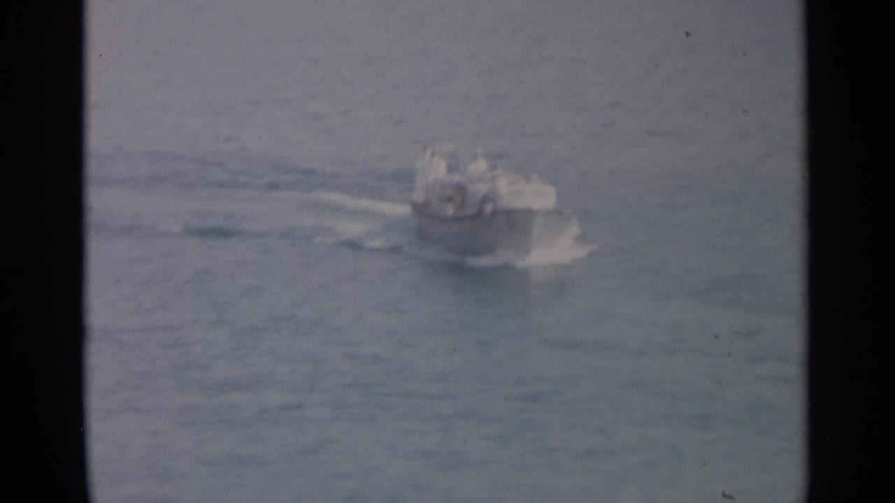 Small motorboat moving across calm water with a white wake.