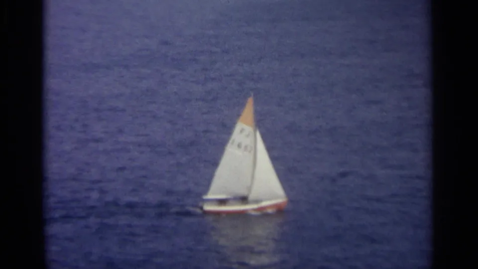 1965 Sicily 8mm frame with a small sailboat on blue harbor water, its white sail marked by an orange tip.