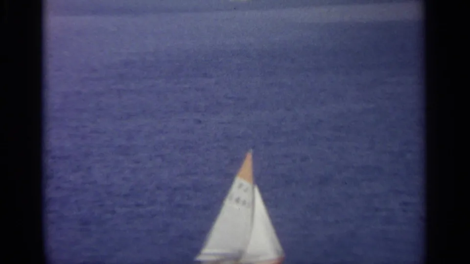 The sailboat continues across the water, softened by grain and focus in the 8mm frame.