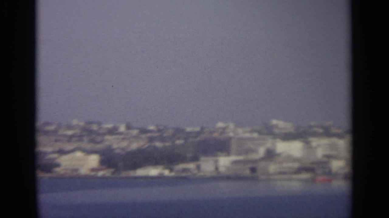 Distant coastal city across blue water under a pale sky.