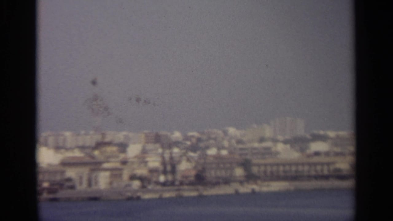 Distant city buildings along water with a tall tower visible.