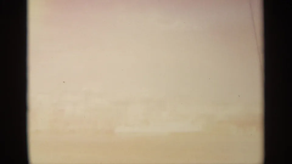 Washed 8mm frame with a faint horizon and shoreline forms, likely part of the same coastal boat sequence.
