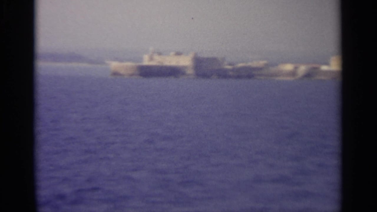 Distant shoreline buildings across blue water with dark 8mm frame borders.