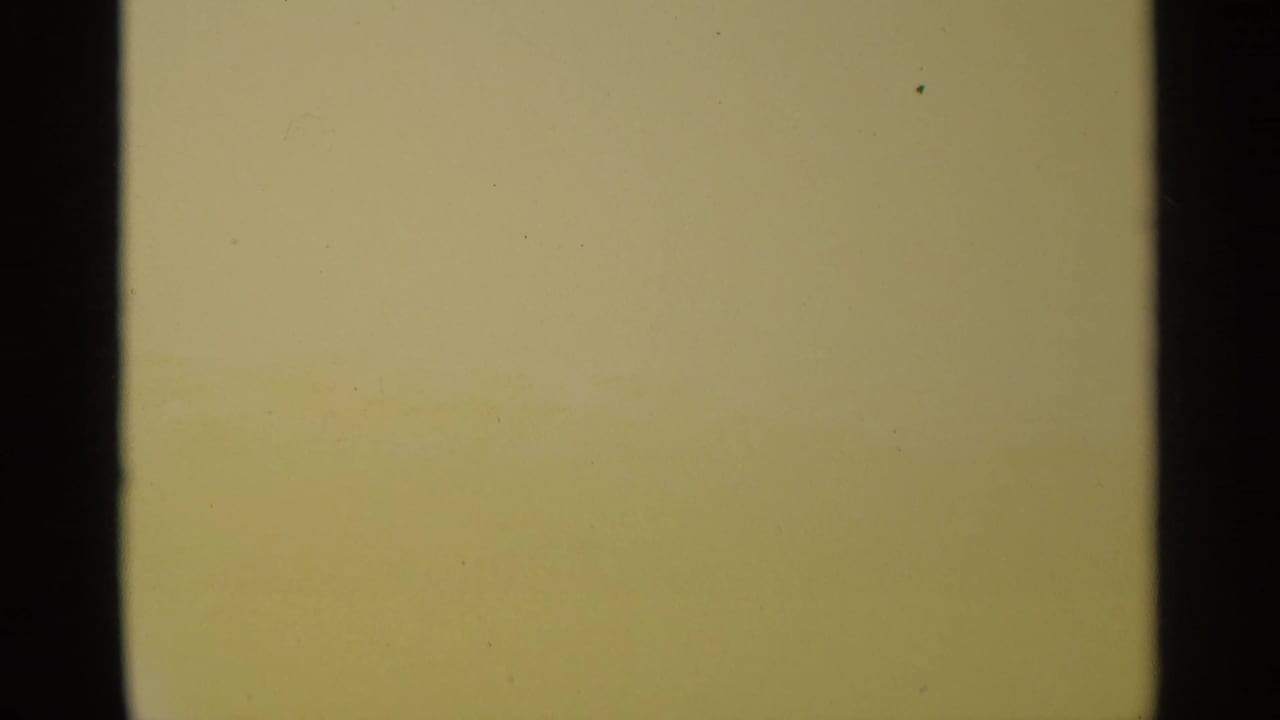 Overexposed pale film frame with dark vertical edges and a warm band near the bottom.