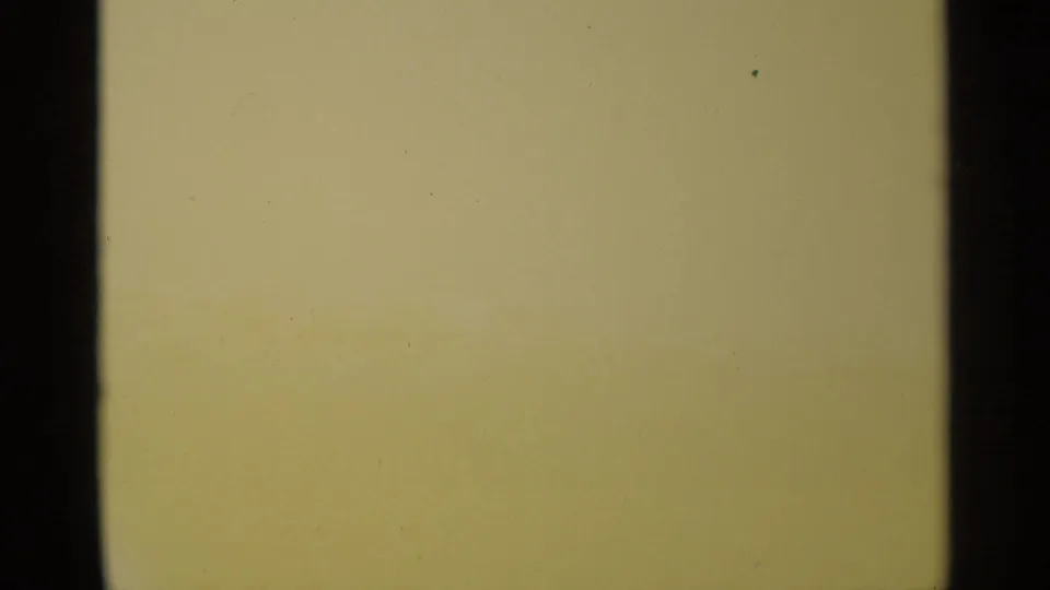 Pale, overexposed 8mm frame with dark gate edges and a warm color shift near the lower edge, likely before the boat scene appears.